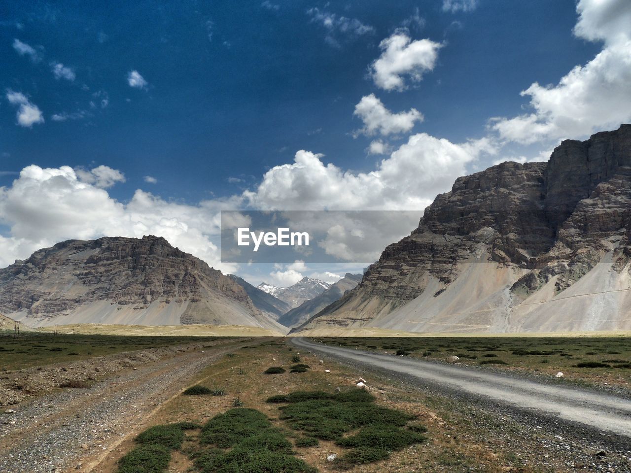 Scenic view of road by mountains against sky