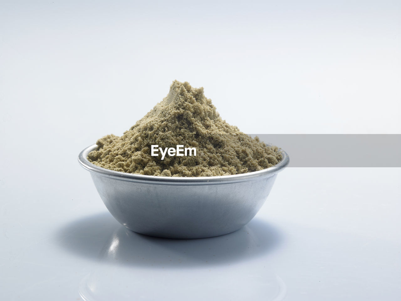 Close-up of cumin powder in bowl against white background