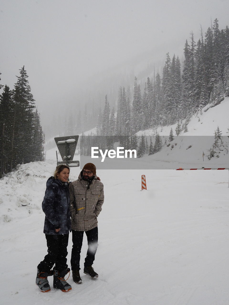 Friends walking on snow covered field during snowfall