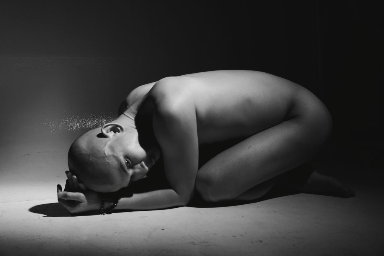 PORTRAIT OF SHIRTLESS BOY LYING ON FLOOR