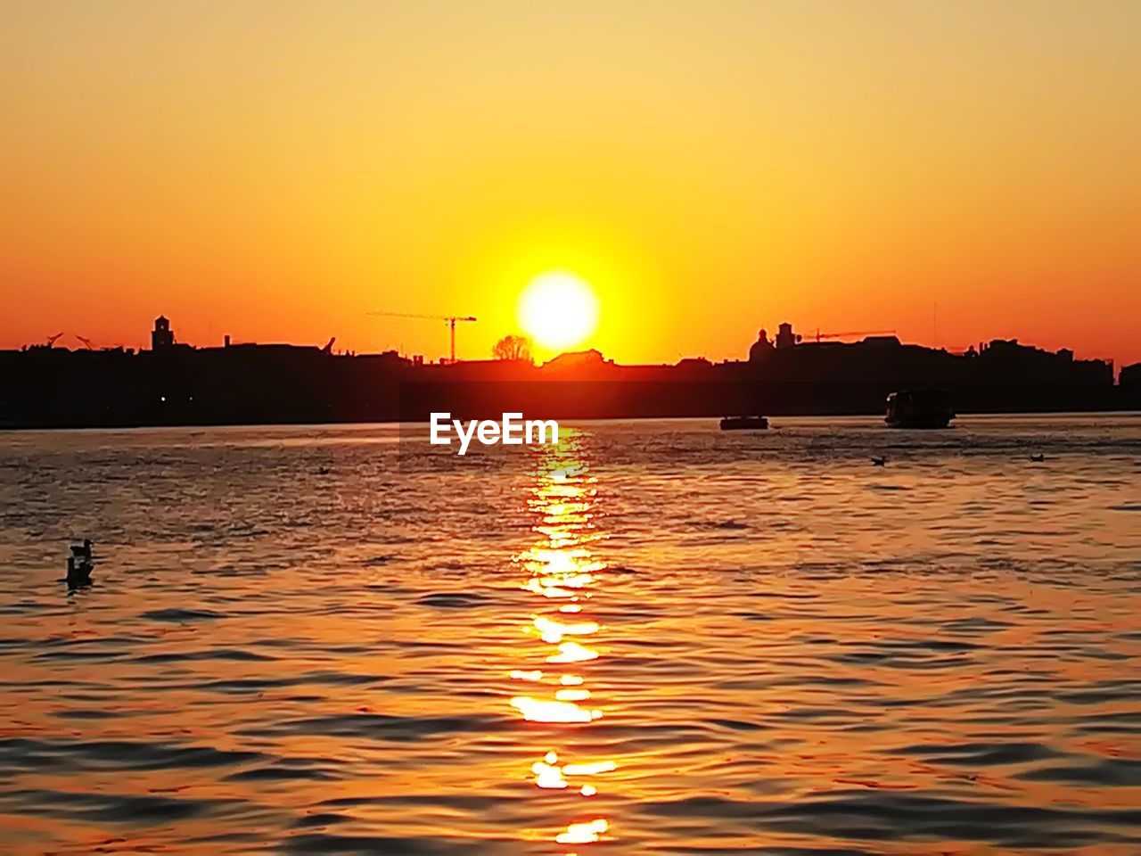 SILHOUETTE BOATS IN SEA AGAINST ORANGE SKY