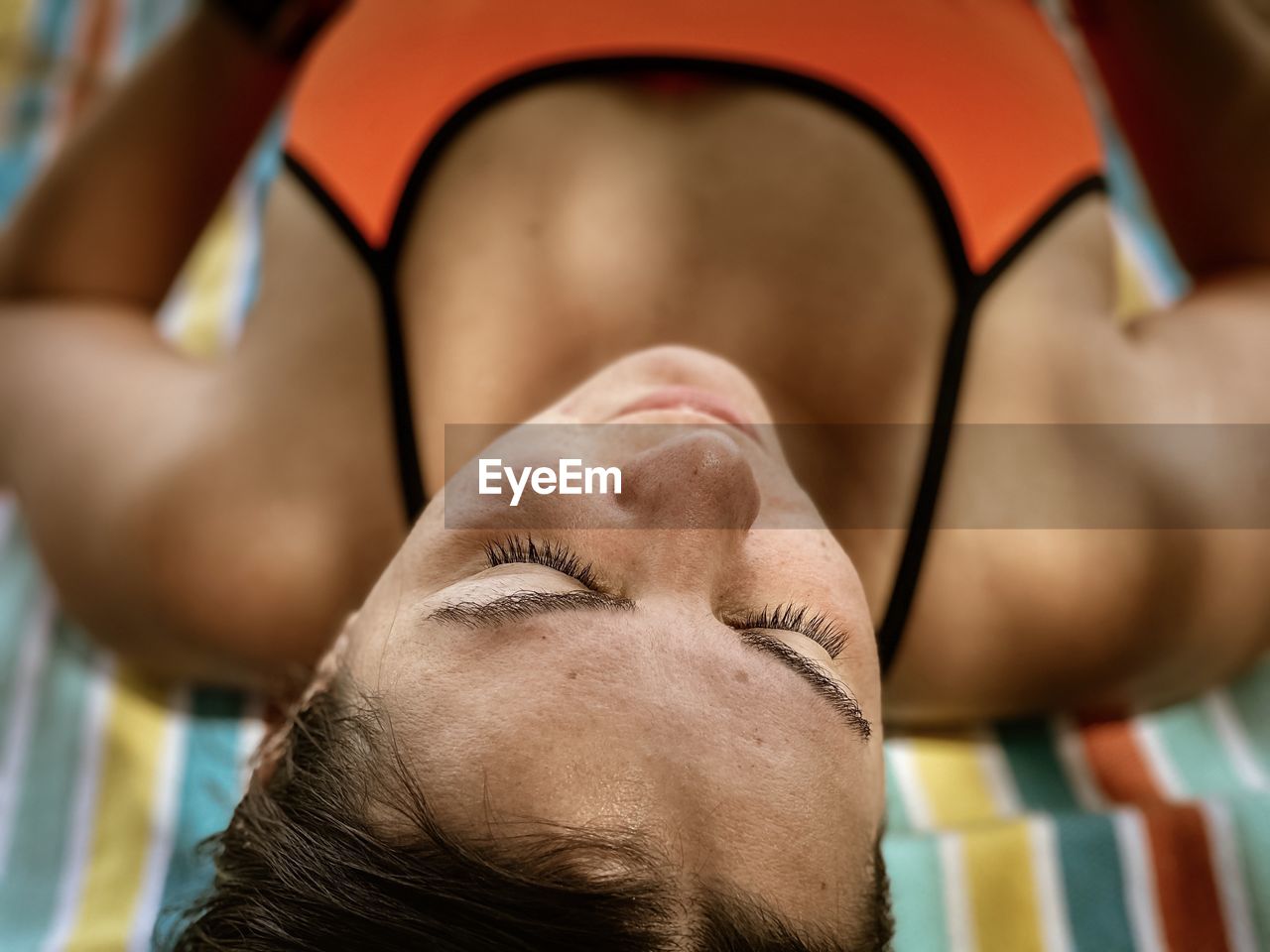 Close-up portrait of woman lying outdoors at beach 