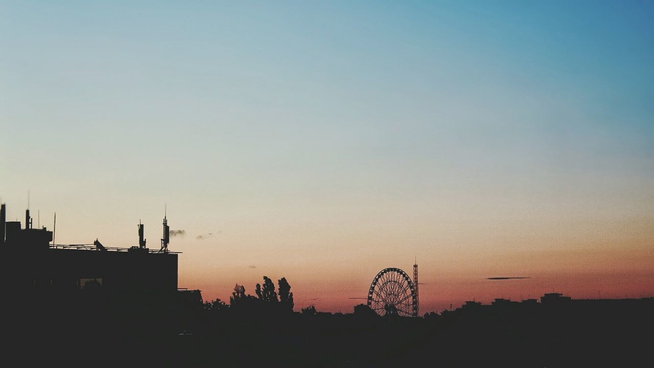 Silhouette of building and ferris wheel against sky