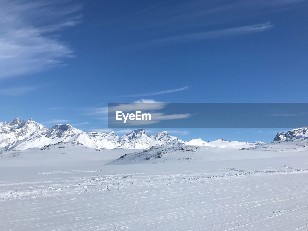 Scenic view of snowcapped mountains against blue sky