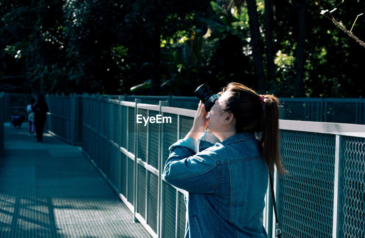 Woman photographing on footbridge