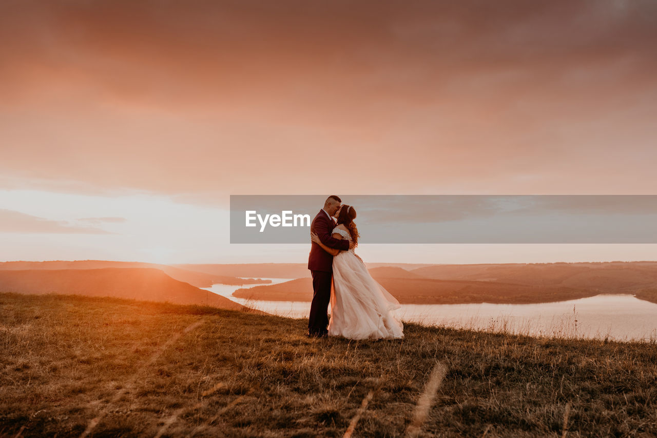 full length of woman standing on field against sky during sunset