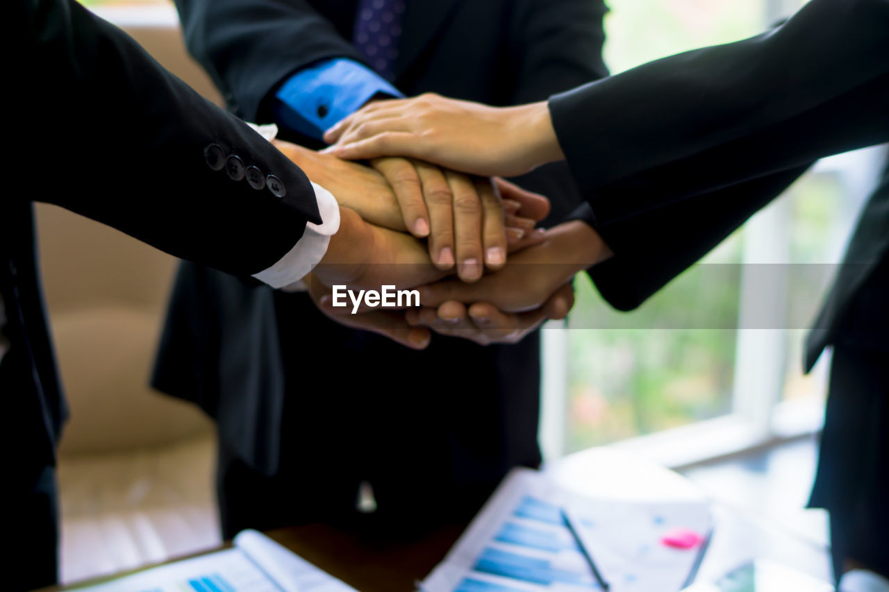 Cropped image of business people stacking hands in office