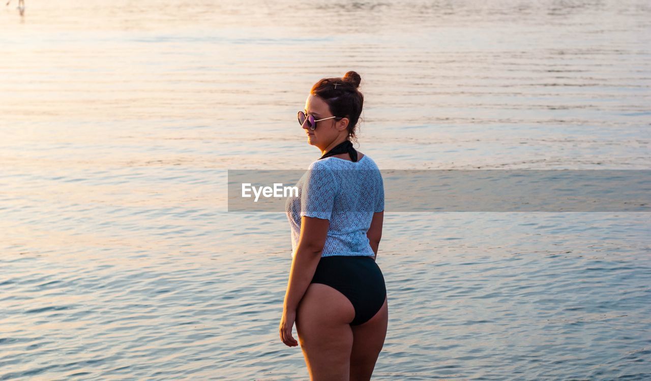 Rear view of woman standing in swimwear at beach