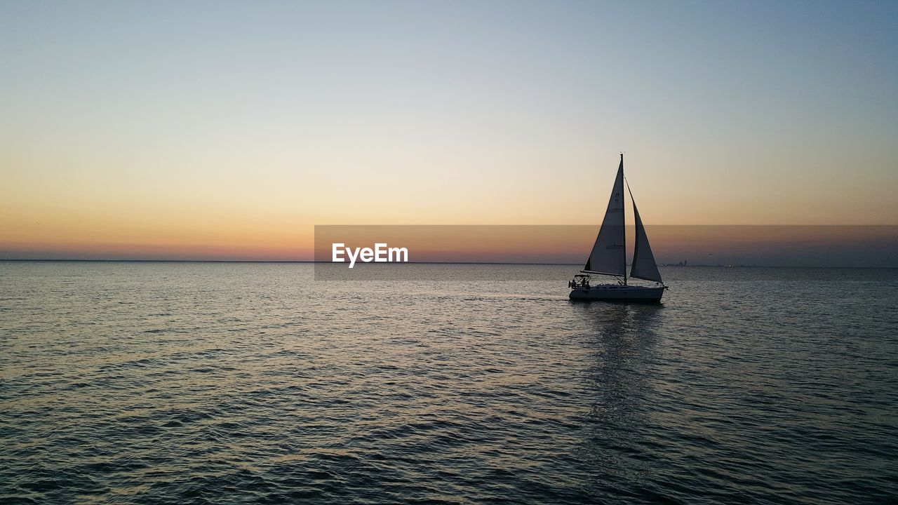 Boat sailing in sea at sunset