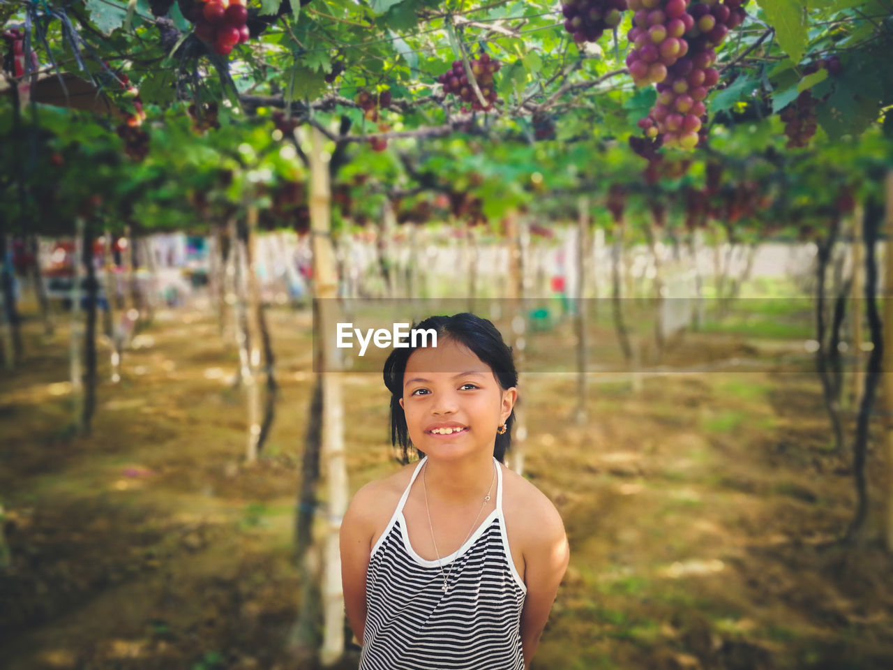 Portrait of girl standing against trees on field