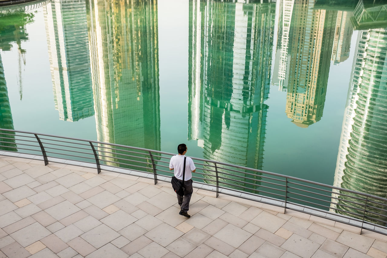 REAR VIEW OF MAN STANDING ON FOOTPATH