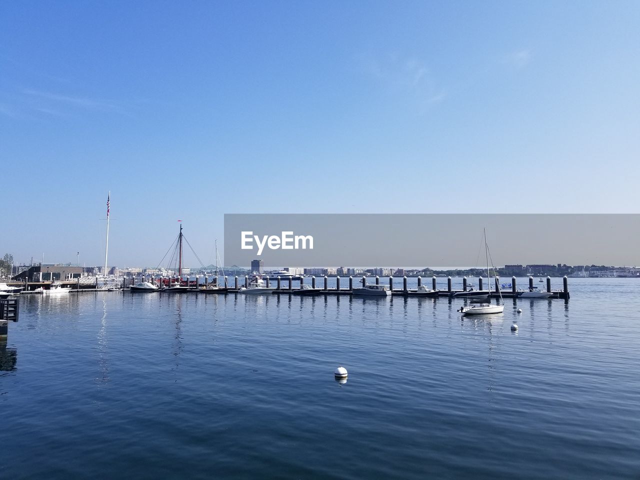 SAILBOATS MOORED IN SEA AGAINST CLEAR SKY