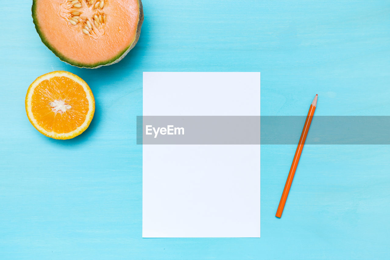 Directly above shot of fruits and paper on turquoise background