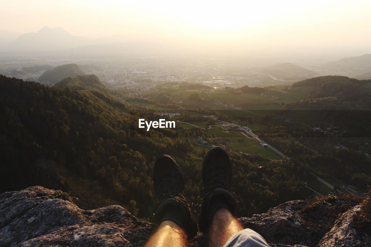 Low section of man against mountains during sunset