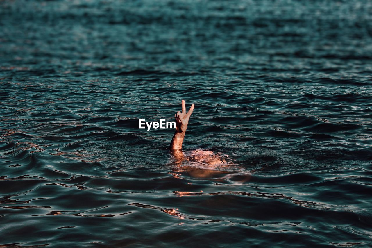 Cropped image of person gesturing while swimming in sea