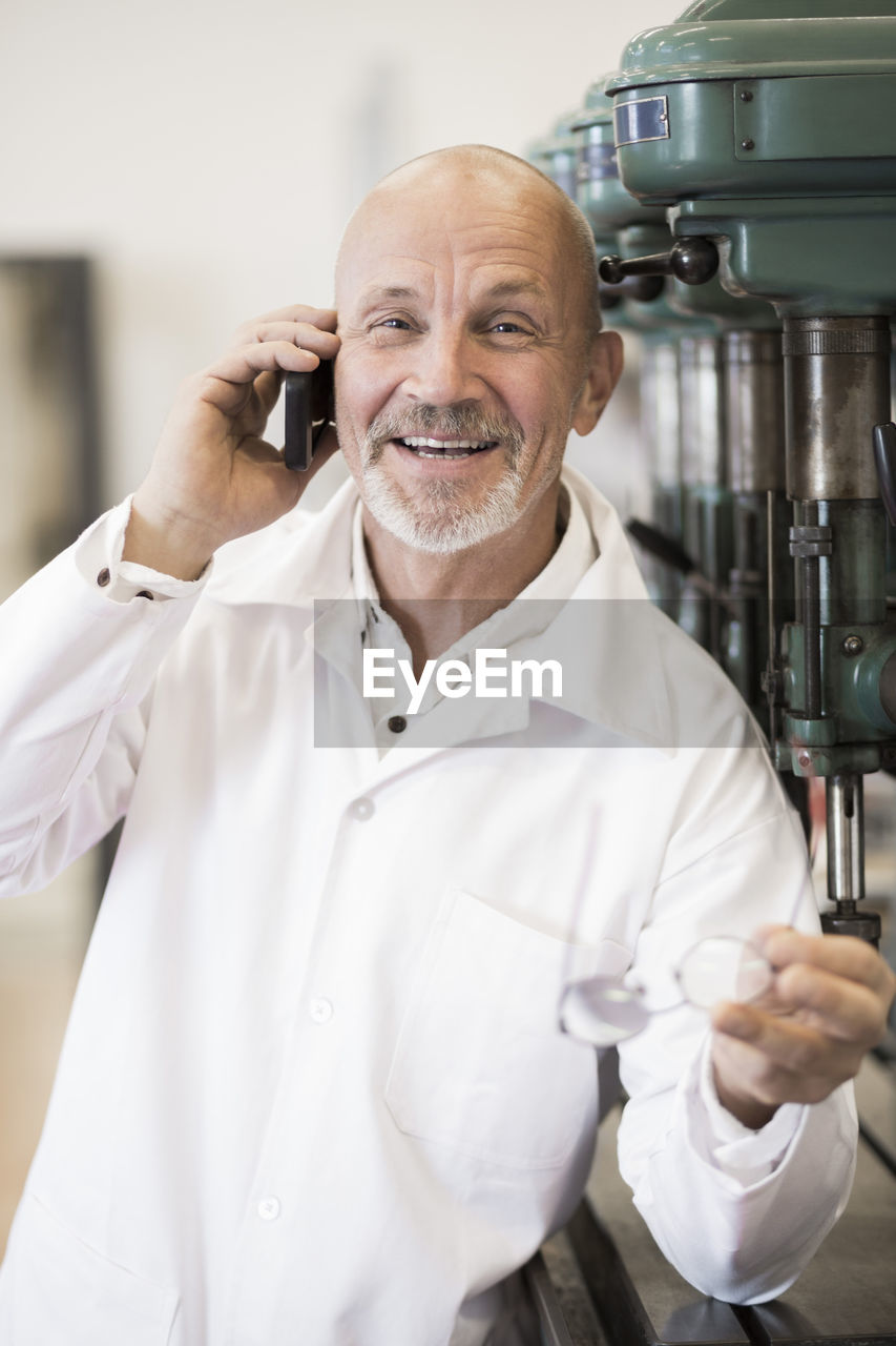 Portrait of smiling engineer answering mobile phone in factory