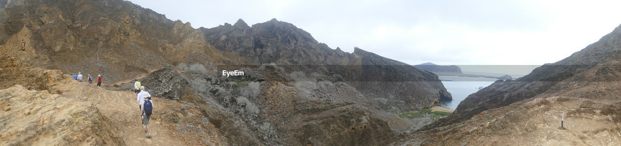 Panoramic shot of man standing on rocky mountains against sky