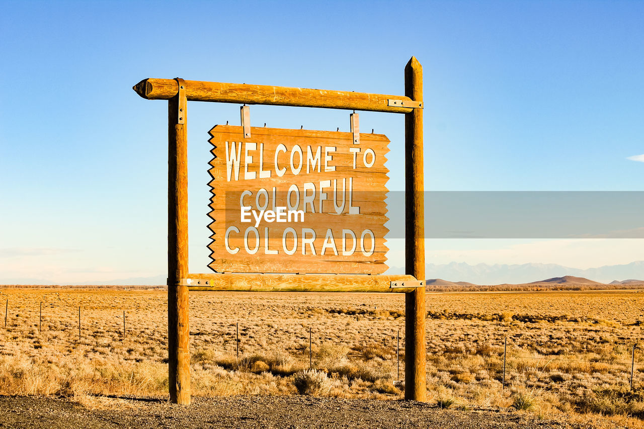 Close-up of welcome to colorado signboard on barren landscape