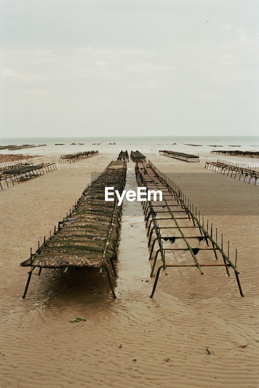 WOODEN POSTS ON BEACH