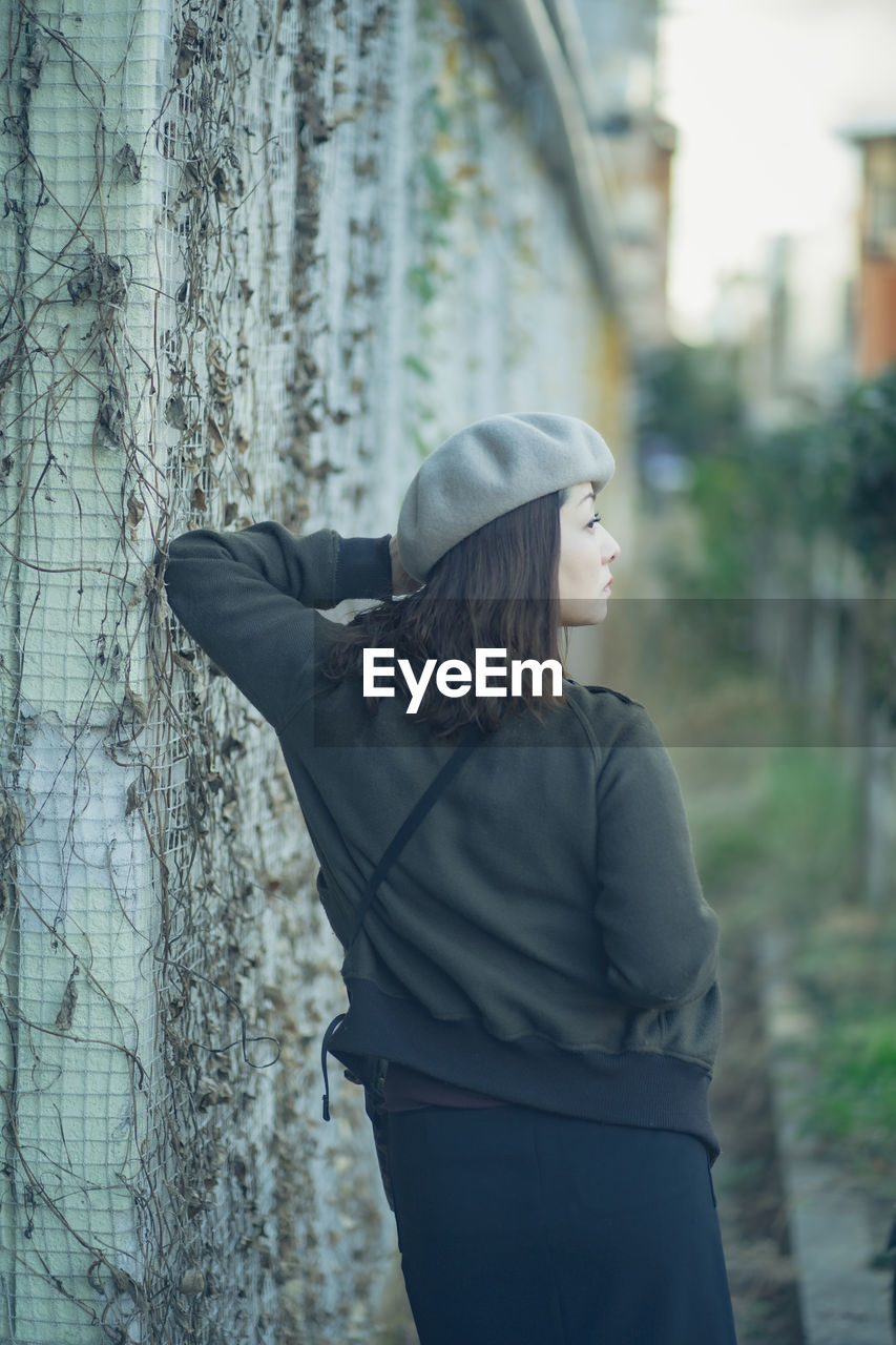 MIDSECTION OF WOMAN STANDING BY PLANTS