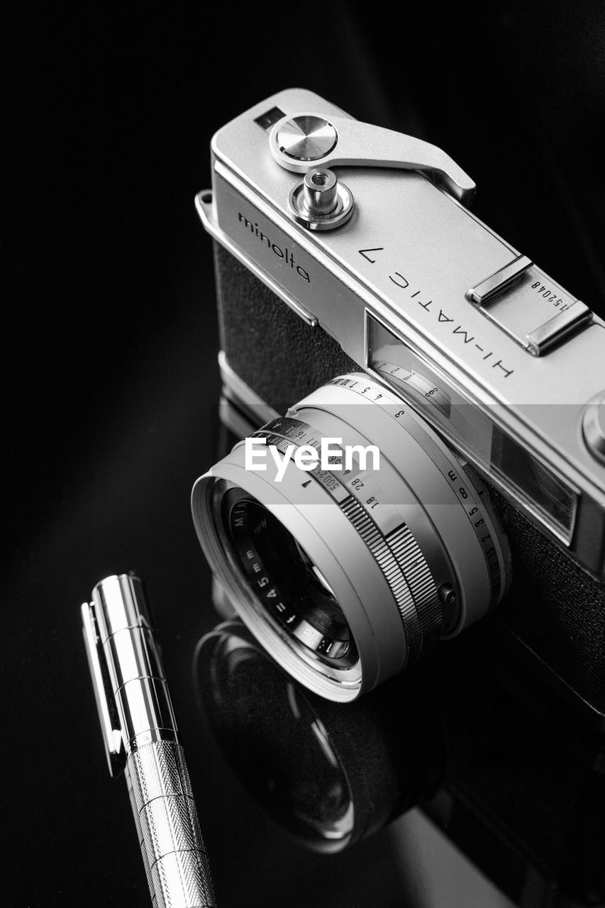 HIGH ANGLE VIEW OF CAMERA ON TABLE AGAINST BLACK BACKGROUND