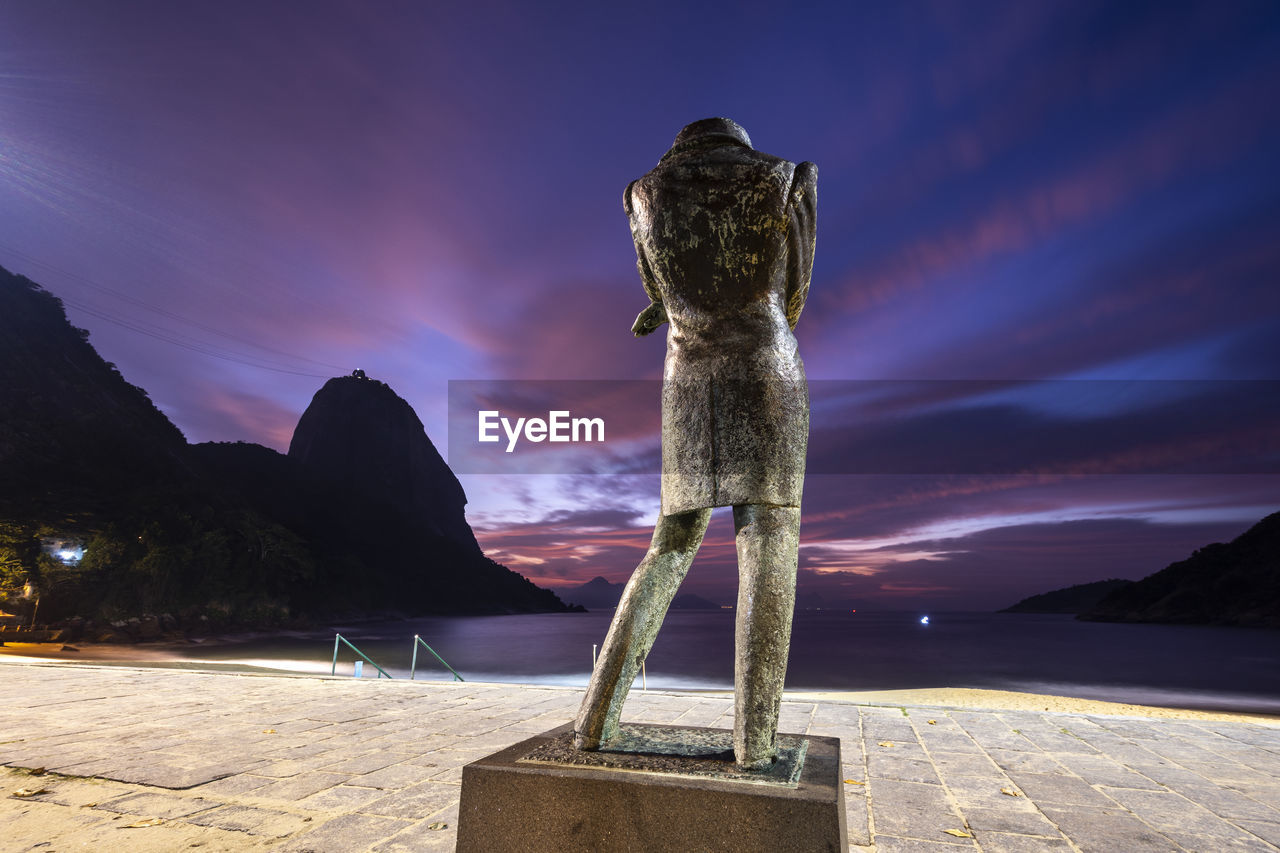 Beautiful sunrise view from beachfront statue to ocean and mountain