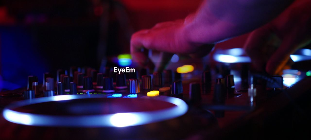 Cropped hand of dj adjusting knobs on sound mixer