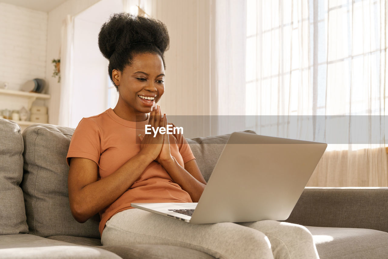 Young woman using laptop while sitting on sofa