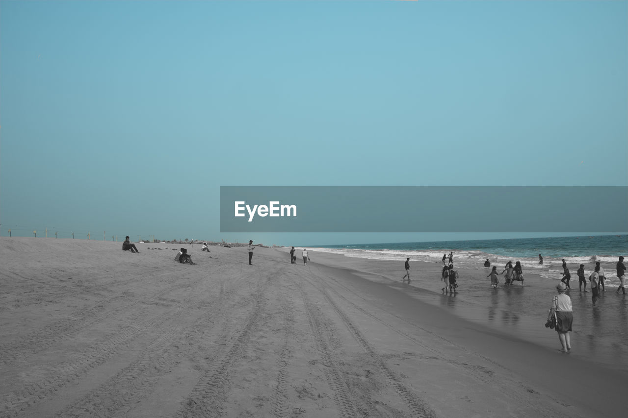 PEOPLE AT BEACH AGAINST CLEAR SKY