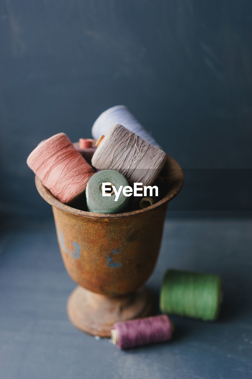 Close-up of spools in rusty metallic container on table