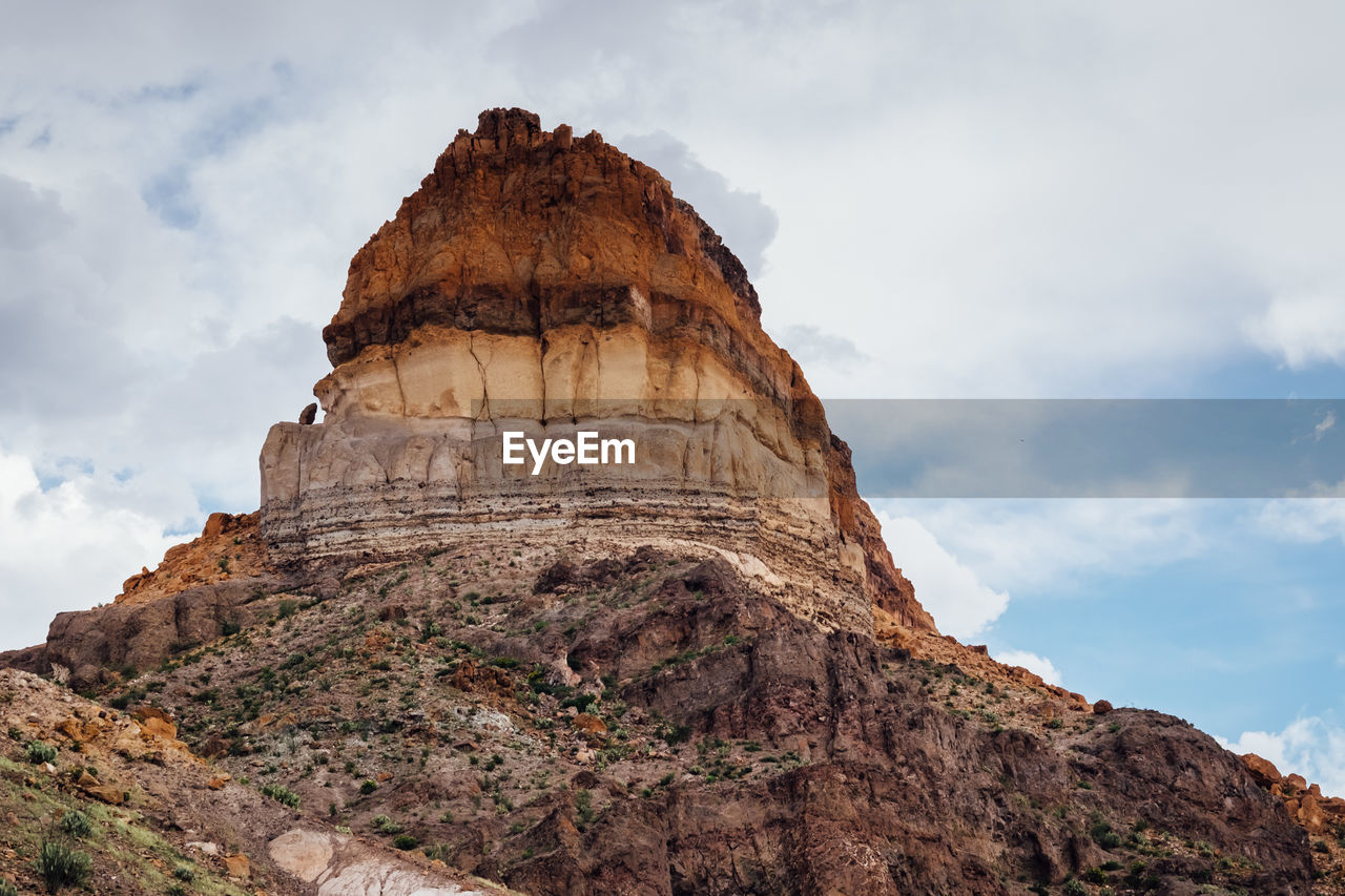 Low angle view of rock formation against cloudy sky