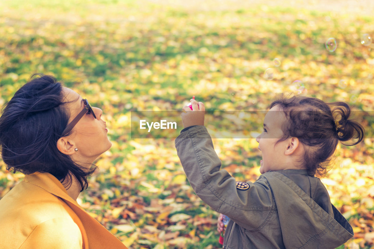 Smiling mother and daughter spending leisure time at park