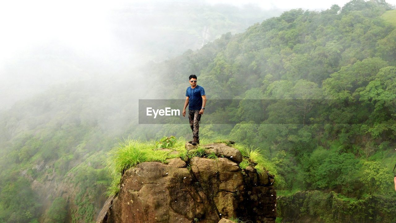 Portrait of man standing on rock against mountain