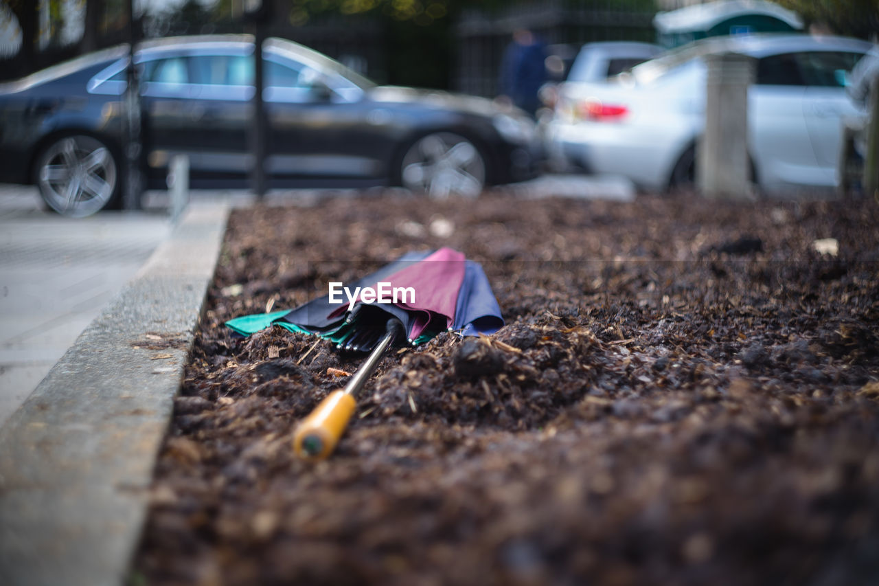 Close-up of umbrella on field against cars