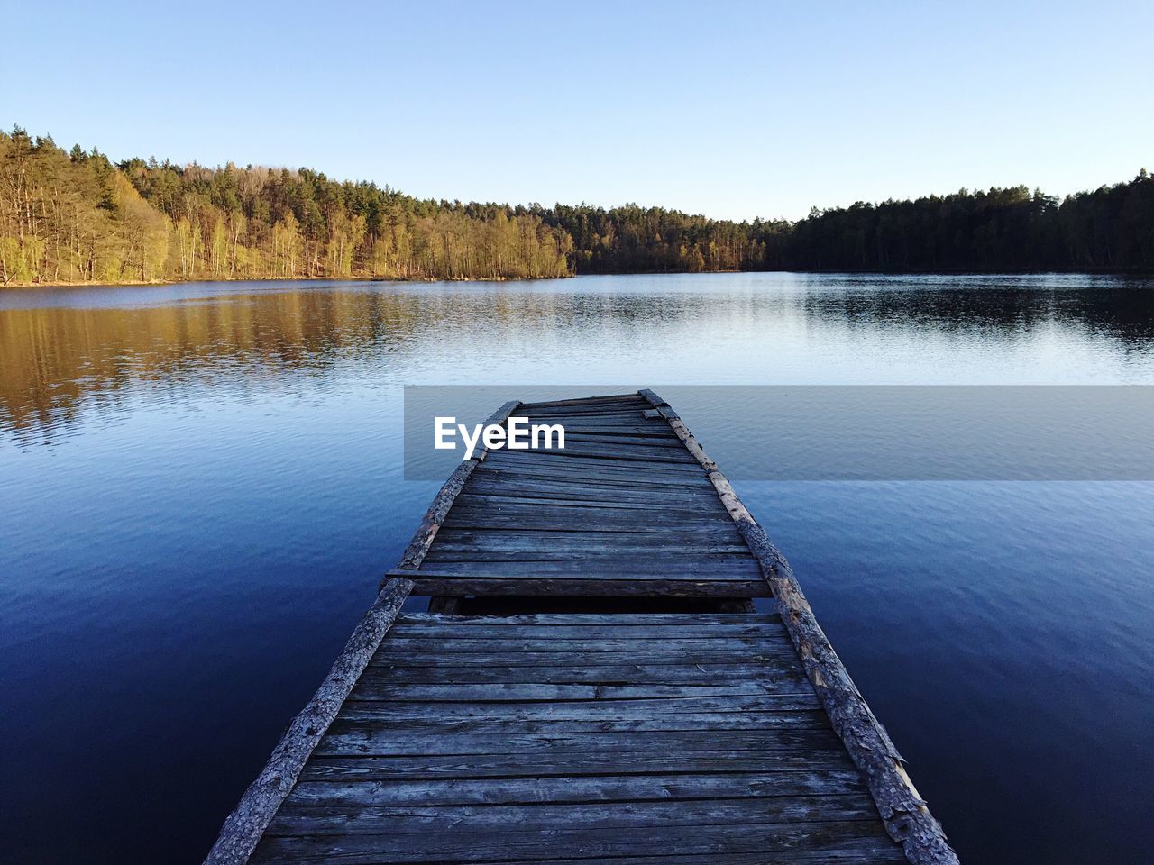 Jetty over lake against clear sky