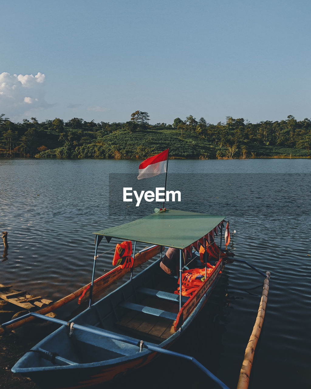 BOAT MOORED ON LAKE AGAINST SKY