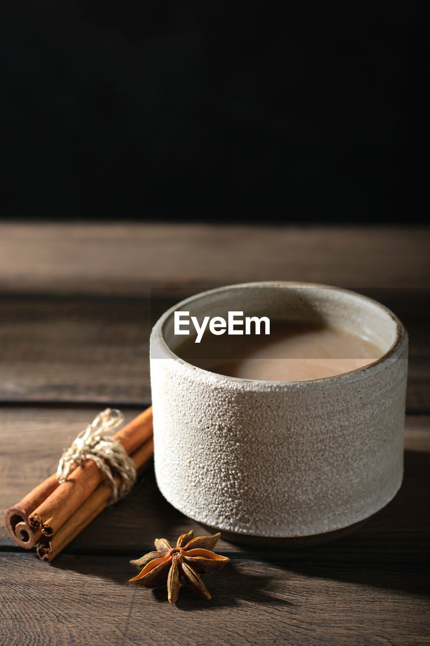Ceramic cup of masala tea with spice on a wooden table
