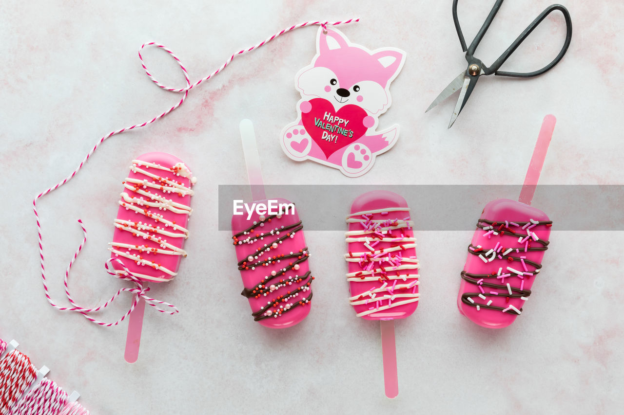 Homemade valentine cakesicle treats with a valentine card attached to one.