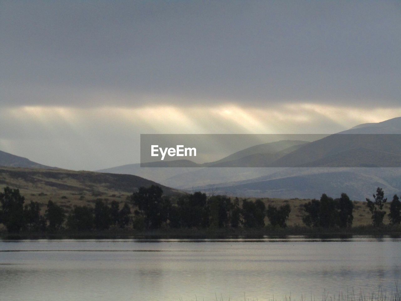 SCENIC VIEW OF MOUNTAINS AND LAKE AGAINST CLOUDY SKY