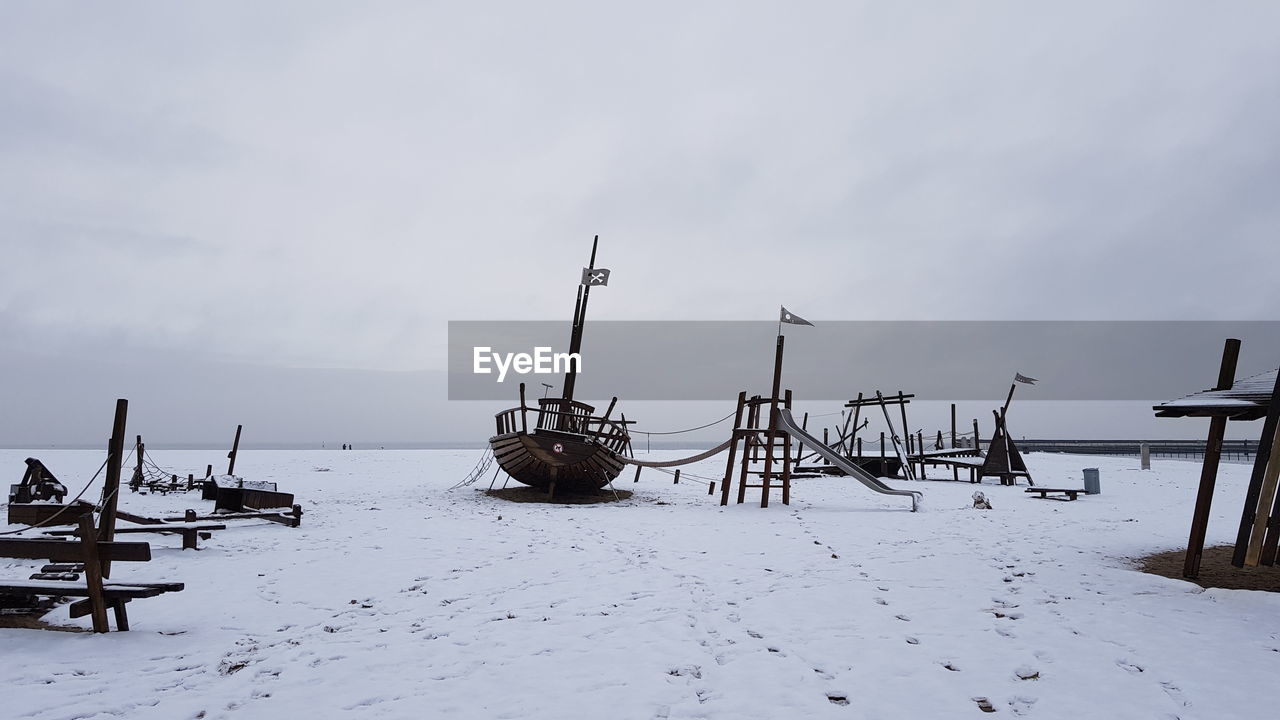 snow, winter, sky, water, cold temperature, environment, nature, scenics - nature, sea, land, landscape, beauty in nature, no people, tranquility, wood, nautical vessel, transportation, cloud, ship, tranquil scene, non-urban scene, overcast, day, vehicle, beach, outdoors, travel, architecture, ocean, boat, social issues, storm, extreme weather, pier, travel destinations, mode of transportation, rural scene