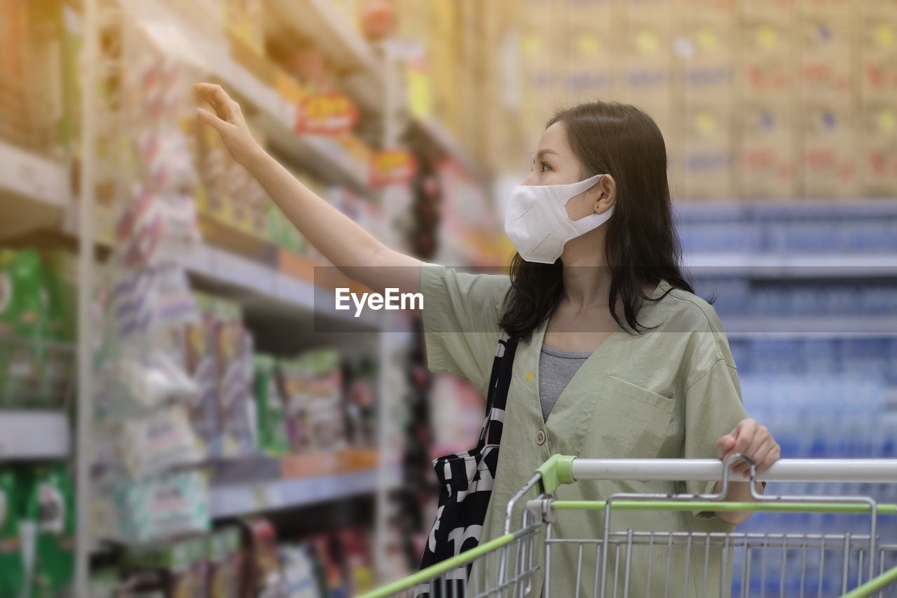 Full length of woman wearing mask at store