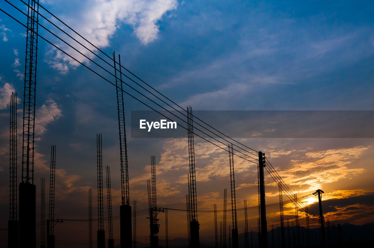 LOW ANGLE VIEW OF SILHOUETTE CRANES AGAINST ORANGE SKY