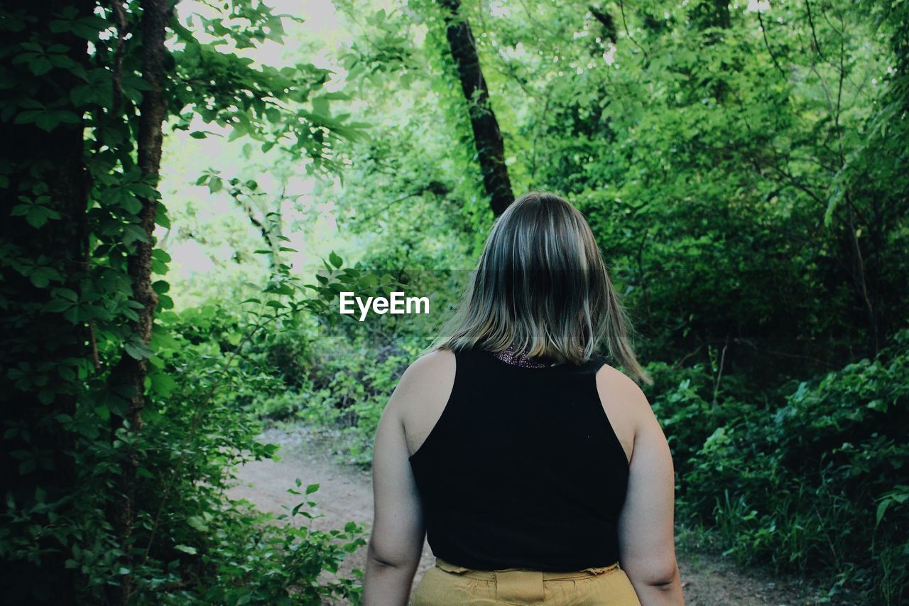 Rear view of woman standing in forest