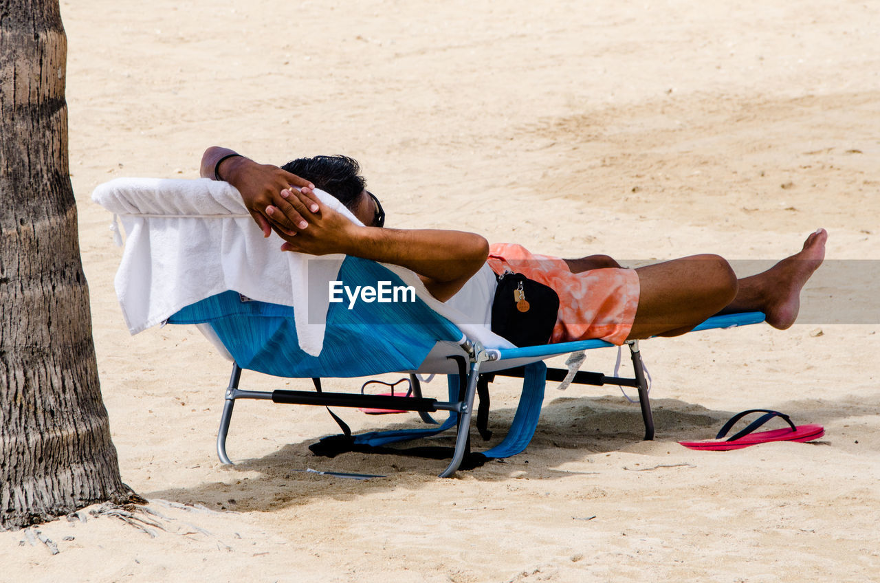 Man relaxing on lounge chair at beach