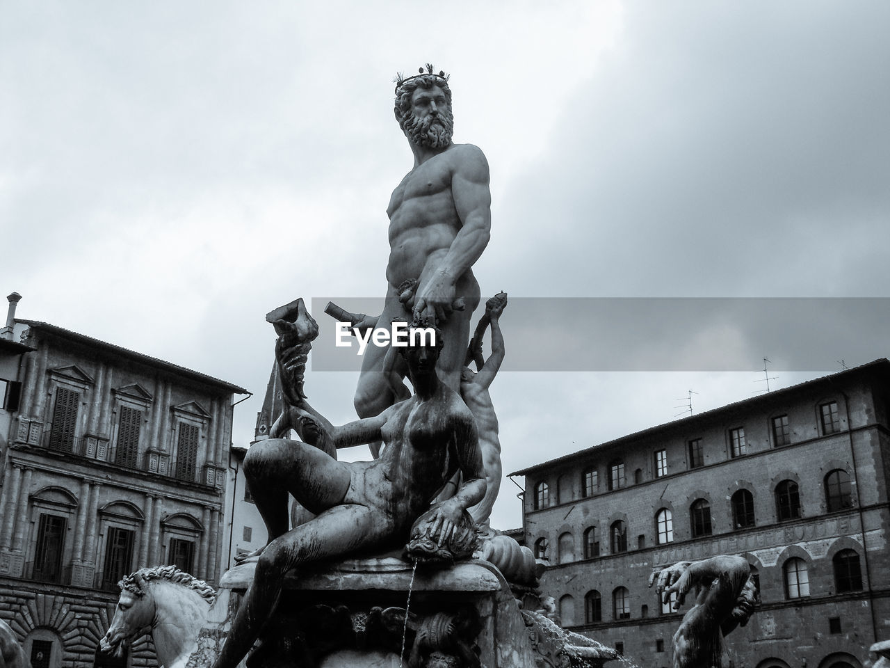 STATUE IN CITY AGAINST CLOUDY SKY