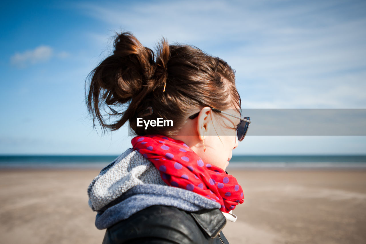 Side view of mid adult woman standing at beach against sky