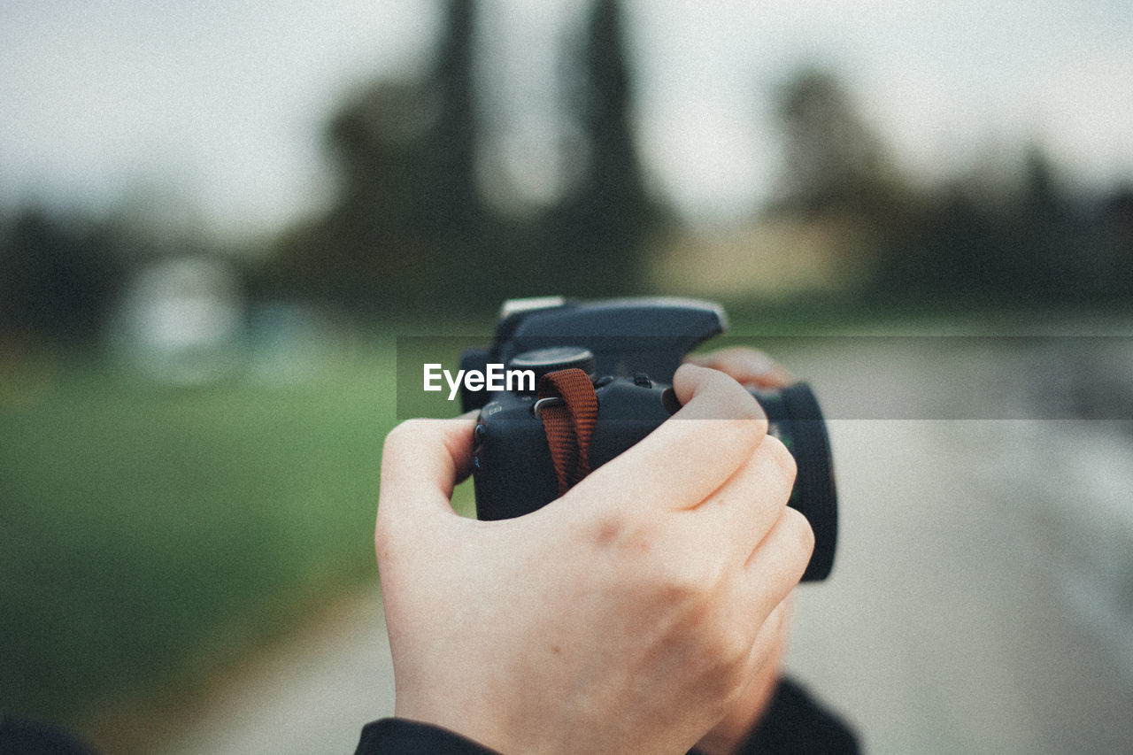 Close-up of hand holding camera outdoors
