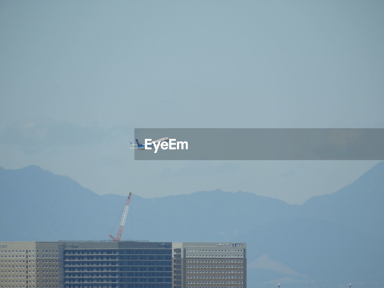 Airplane flying over mountain against sky