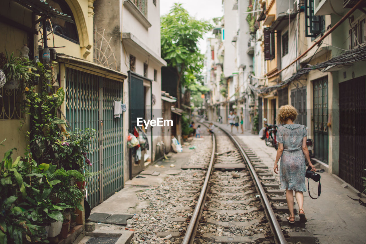 Woman walking on railroad track in city