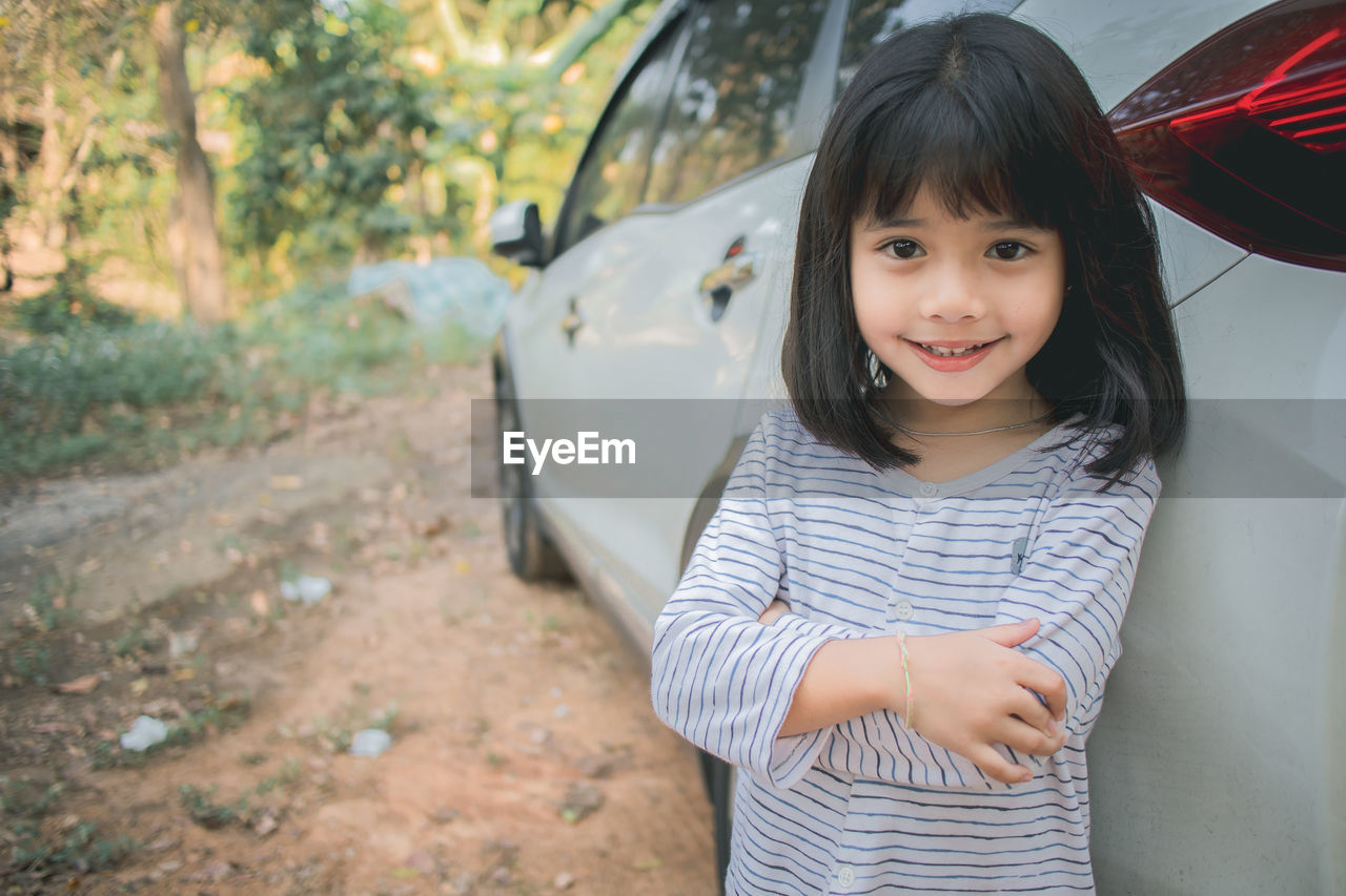 Portrait of smiling girl standing by car